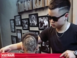 Молодой мастер-татуировщик по волосам