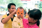 A volunteer wears a mask for a kid at the National Hospital of Pediatrics. Photo: Cong Dat.