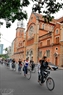 Une groupe de cyclistes passent devant la cathédrale Notre-Dame, Ho Chi Minh-Ville. 