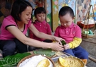 The teacher helps children to tie their cakes.